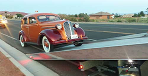 orange vintage car being loaded onto a tow truck