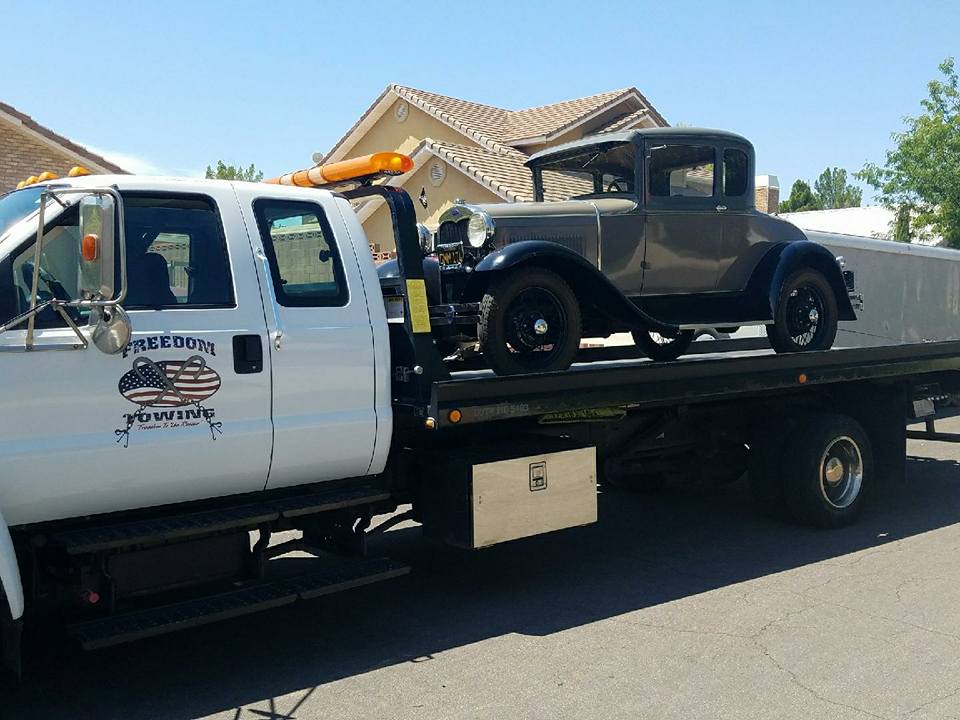 black vintage car on a flat bed tow truck